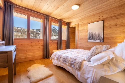 a bedroom with a bed and a desk and windows at Chalet Mountainside avec sauna et jacuzzi à 200m des pistes in Vars