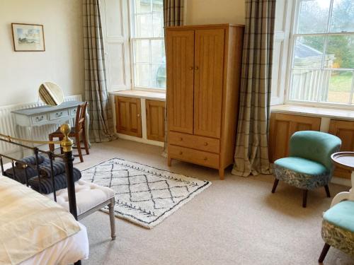 a bedroom with a bed and a dresser and two windows at Meldon Cottage in Morpeth, Northumberland in Morpeth