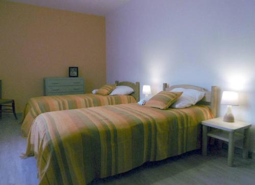 Un dormitorio con 2 camas y una mesa con lámparas. en Bienvenue au gîte de Claret, en Casseneuil