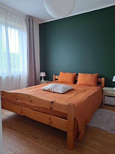 a large wooden bed in a bedroom with a green wall at logement avec jardin de bord Mer PORT NAVALO in Arzon