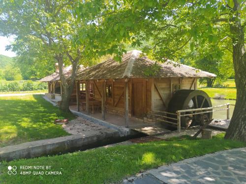 a small building with a large wheel in a park at Vodenica Lug in Strmosten