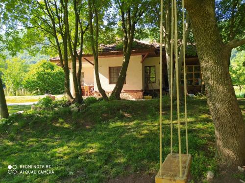 a house in a yard with trees and a swing at Vodenica Lug in Strmosten