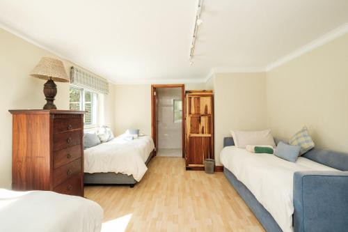 1 dormitorio con 2 camas y sofá azul en 10 St Andrews Avenue en Natureʼs Valley