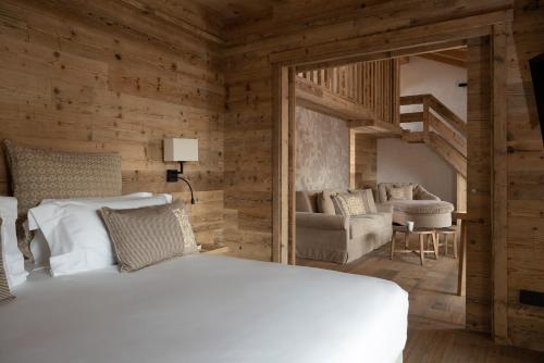 a bedroom with a white bed and a living room at Hotel Baita Dei Pini in Bormio