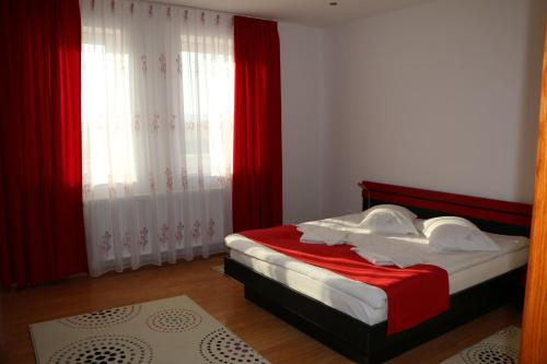 a bedroom with a bed with red and white sheets at Sanderson Apartments in Miercurea-Ciuc