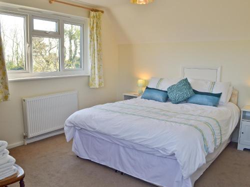 a bedroom with a large white bed with blue pillows at Sandrock in Brighstone