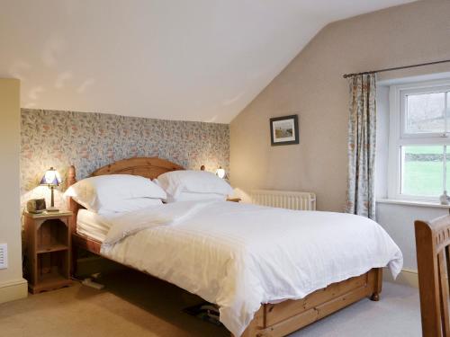 a bedroom with a large bed with white sheets and a window at Brasscam in Rosthwaite