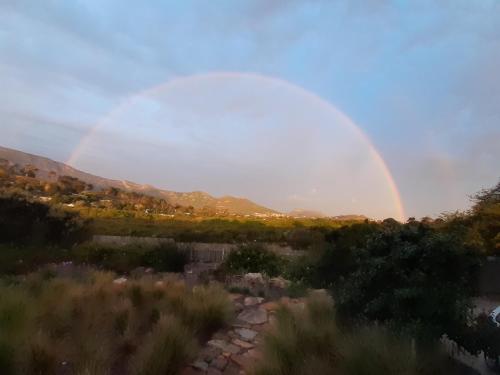 a rainbow in the sky over a field at Selkie - Two Restful Studio Apartments near Noordhoek Beach & Restaurants in Noordhoek