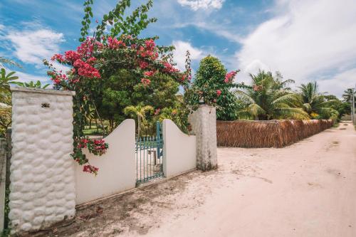 a white fence with pink flowers on a road at Ocacocar - Milagres in São Miguel dos Milagres