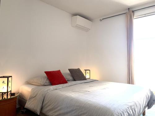 sypialnia z łóżkiem z białą pościelą i czerwonymi poduszkami w obiekcie Appartement climatisé entre plage et port de Saint Mandrier w mieście Saint-Mandrier-sur-Mer