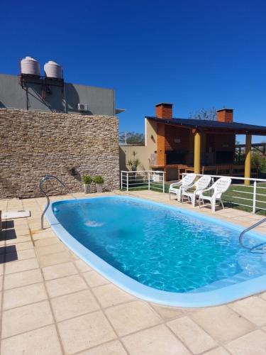 a large swimming pool on a patio with two chairs at Complejo Amarelo in Chajarí