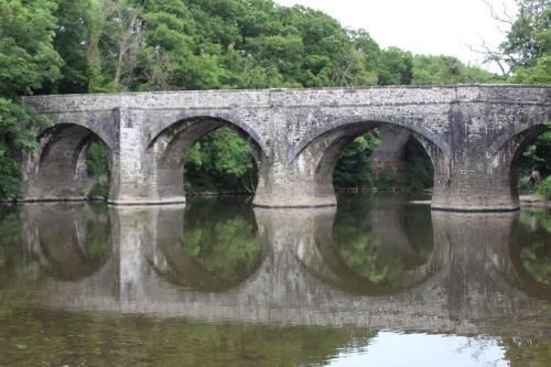 a stone bridge over a river with reflections in the water at 3 bedroom terrace holiday home in Great Torrington