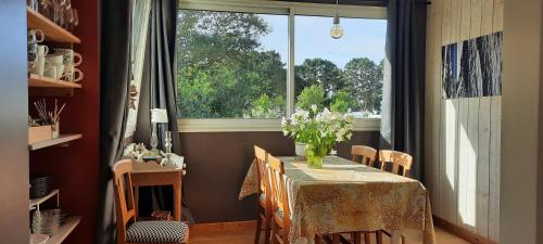 una sala da pranzo con tavolo e finestra di logement avec jardin de bord Mer PORT NAVALO ad Arzon