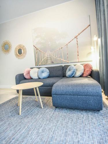 a living room with a blue couch and a table at Apartamenty Na Wyspie - Baltic Park - Apartamenty z sypialnią i parkingiem - ul Uzdrowiskowa 24-34 in Świnoujście