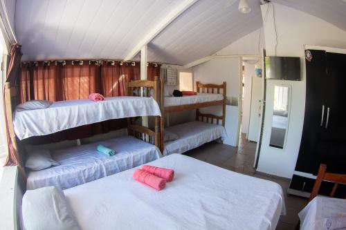a room with three bunk beds and two tables at Pousada Pérola do Guarujá Ltda- Me in Guarujá
