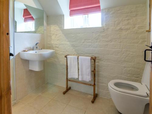La salle de bains blanche est pourvue d'un lavabo et de toilettes. dans l'établissement The Long Barn, à Ampney Crucis