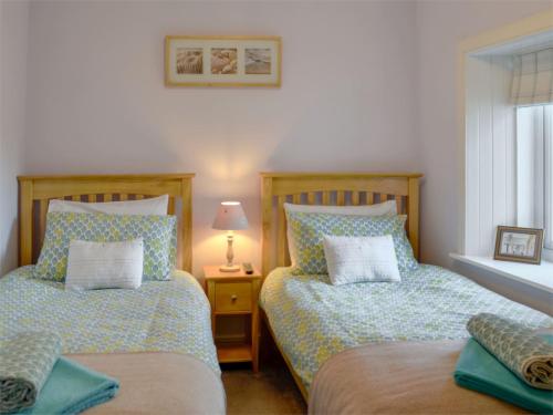 twee bedden naast elkaar in een slaapkamer bij River Cottage in Bladnoch