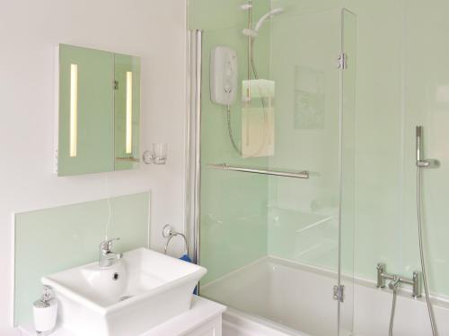 een witte badkamer met een wastafel en een douche bij River Cottage in Bladnoch
