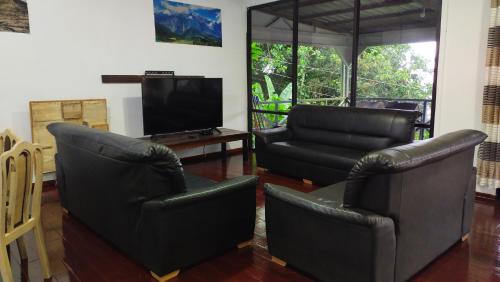 sala de estar con 2 sillas de cuero y TV en Happy Garden, 