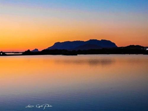 a sunset over a body of water with mountains in the background at Domus de Diana in Olbia