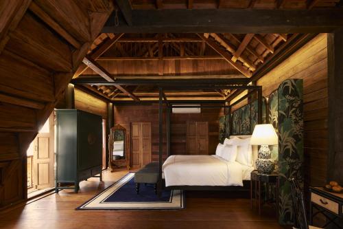 a bedroom with a bed in a room with wooden walls at Aleenta Retreat Chiang Mai in Chiang Mai