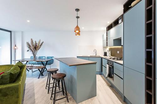 ロンドンにあるDuplex Two-Bed Apartment Near Tower Bridgeのキッチン(青いキャビネット、テーブル、ソファ付)