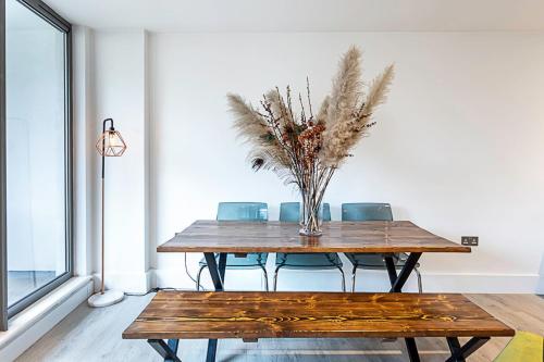 a dining room table with chairs and a vase with feathers at Duplex Two-Bed Apartment Near Tower Bridge in London