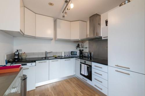 cocina con armarios blancos y suelo de madera en Regent's Canal View Apartment, en Londres