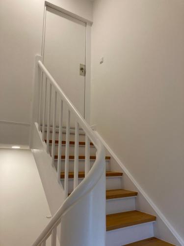 a white staircase with white walls and wooden floors at City-Apartment Düsseldorf in Düsseldorf