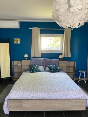 una camera da letto con un grande letto con pareti blu di Appartement indépendant le Mahana a Magalas