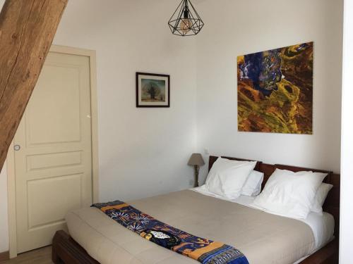 a bedroom with a bed and a painting on the wall at La Closeraie in Noyers-sur-Cher