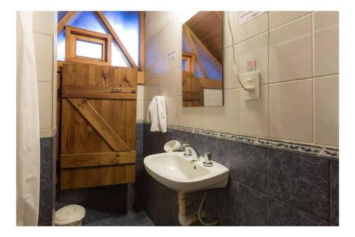 a bathroom with a sink and a mirror and a toilet at Home Cabaña Grande de Angostura in Villa La Angostura