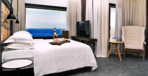 a bedroom with a bed with a bottle of wine on it at Myconian Avaton, a Member of Design Hotels in Elia Beach