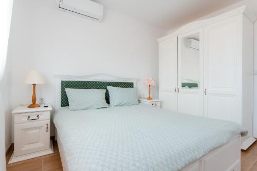 a white bedroom with a large bed with blue sheets at Casa Mavis in Mahmudia
