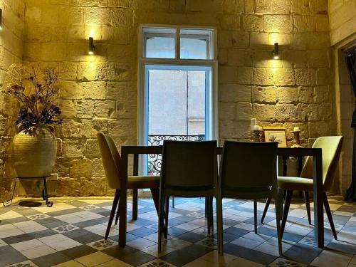 Un comedor con mesa y sillas y una ventana. en House of Character in Valletta, en La Valeta