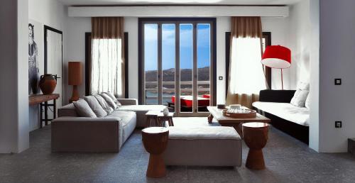 a living room with white furniture and a large window at Myconian Avaton, a Member of Design Hotels in Elia Beach