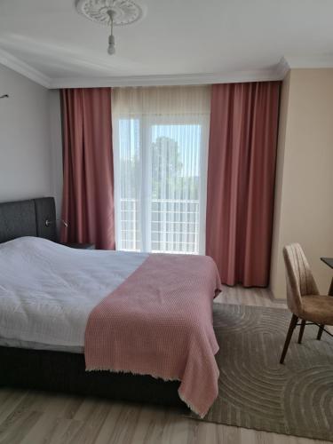 1 dormitorio con 1 cama y una ventana con cortinas rojas en Airport Budget Inn en Arnavutköy