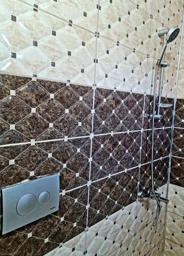 a shower in a bathroom with brown and white tiles at Airport Budget Inn in Arnavutköy