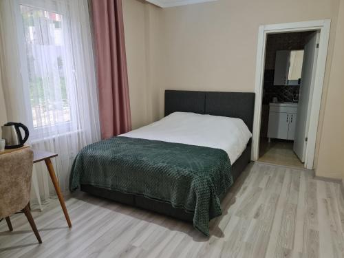 een slaapkamer met een bed met een groene deken bij Airport Budget Inn in Arnavutköy