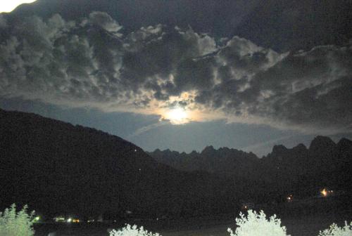 a view of the sun poking out from behind some mountains at Frühstückspension Pachler in Gosau