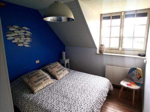 een slaapkamer met een blauwe muur en een bed met kussens bij Les Sableaux, les portes du Marquenterre in Saint-Quentin-en-Tourmont