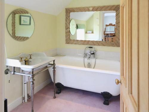 a bathroom with a tub and a sink and a mirror at Cotswolds Farm in Miserden