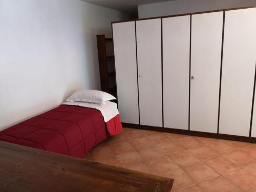 um quarto com armários brancos e uma cama vermelha em Garden's House em Pietrasanta