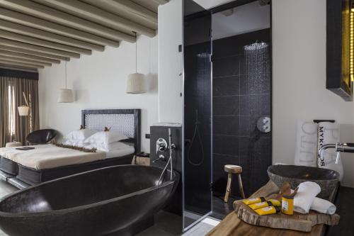 a bathroom with a black tub and a bed at Myconian Utopia Relais & Chateaux in Elia Beach