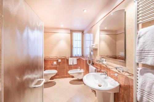 a bathroom with two toilets and a sink and a mirror at Hotel Relais Orsingher in Fiera di Primiero