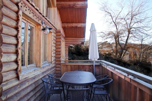 a table and chairs on a porch with an umbrella at Chalet Shaimoa in Font-Romeu-Odeillo-Via