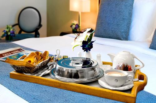a tray with food and a cup of coffee on a bed at Elite Byblos Hotel in Dubai