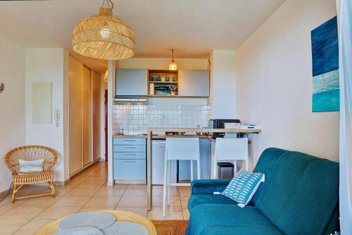 uma sala de estar com um sofá azul e uma cozinha em Le Blue Lagoon - apt T2 Cap Homard em Grand Fond