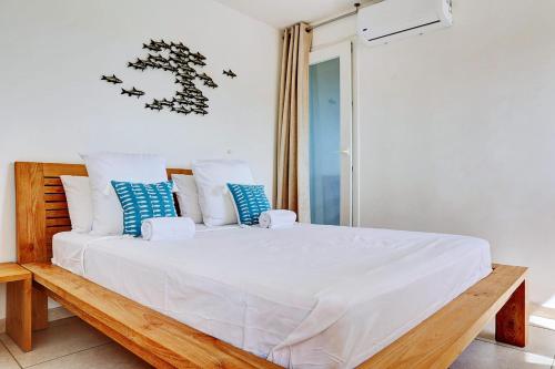 a bedroom with a white bed with blue and white pillows at Le Blue Lagoon - apt T2 Cap Homard in Grand Fond