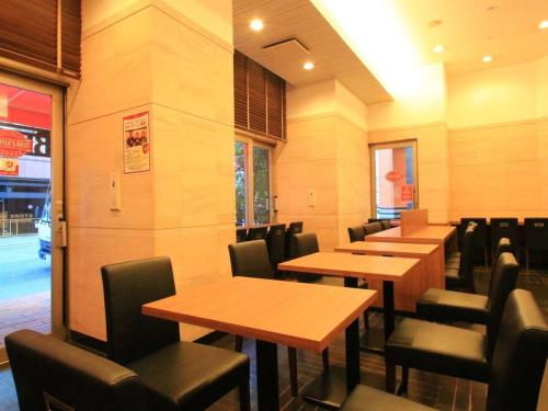 a dining room with wooden tables and chairs at APA Hotel Kobe Sannomiya in Kobe